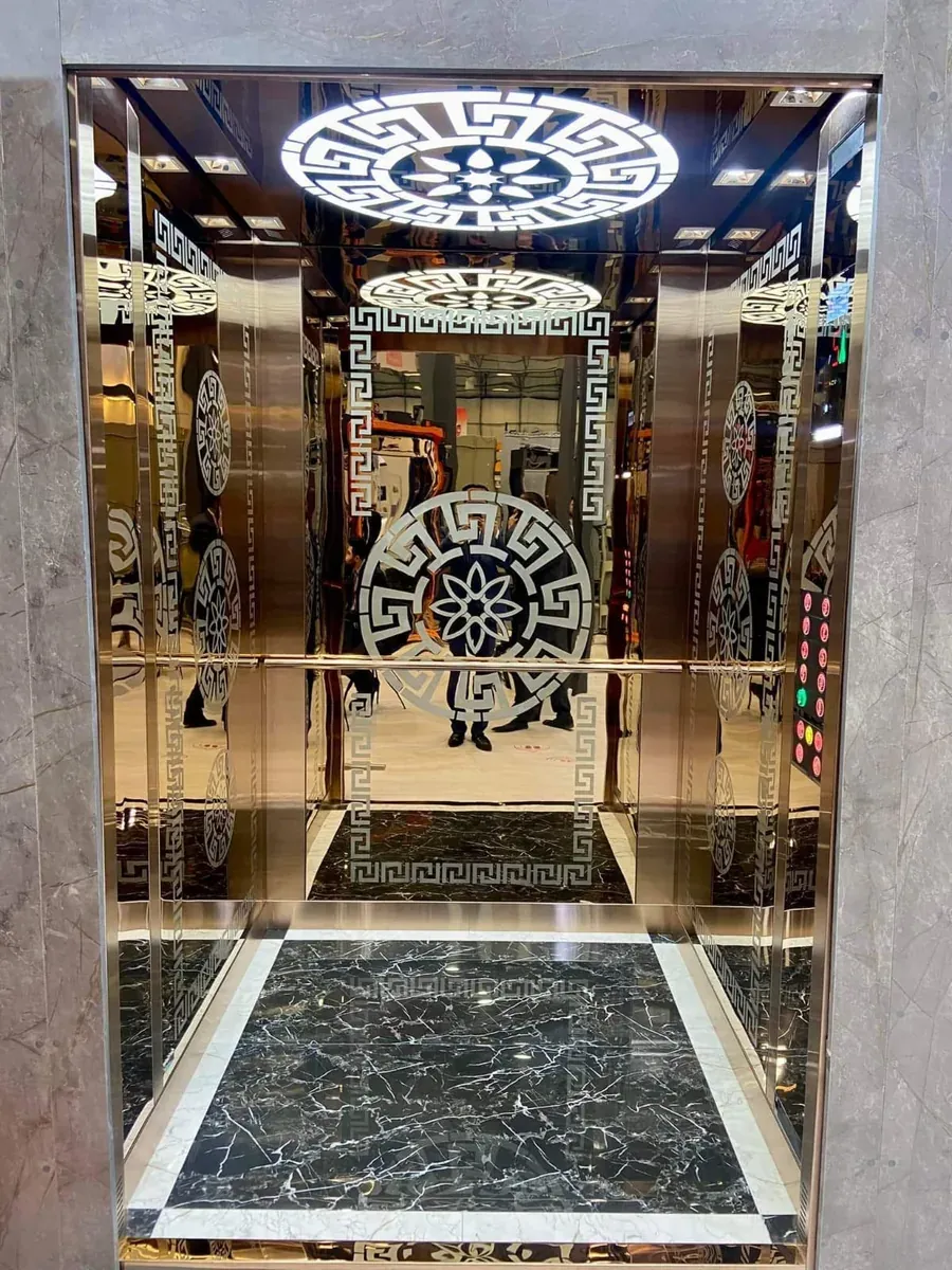 Mirror-gold cabin with etched Greek-key panels and a black marble floor