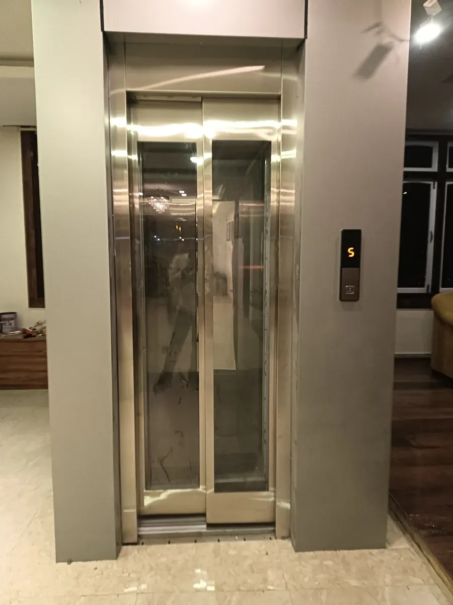 Home lift with glass-vision landing doors in a residential lobby