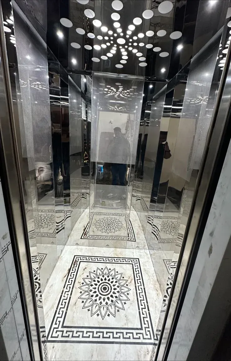 Stainless cabin with a ring-light ceiling and patterned marble floor